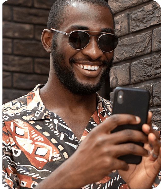 A picture of a black man smiling while staring at his phone